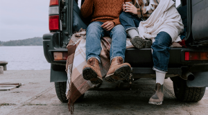 Couple wrapped up warm, sitting in the open boot of their car